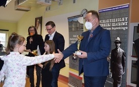 na zdjęciu widać wręczenie nagrody w konkursie szachowym- dyrektor wręcza nagrodę uczennicy klas młodszych